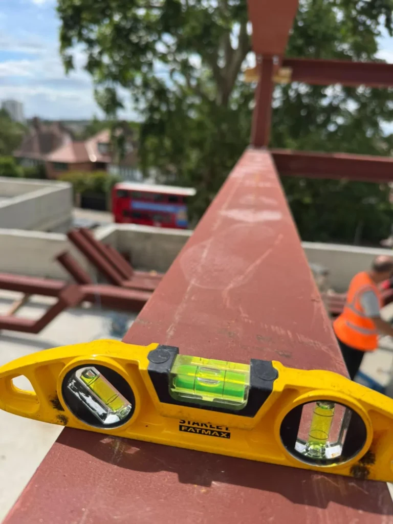 Spirit level used to check the alignment of a structural steel roof frame during installation in North London.