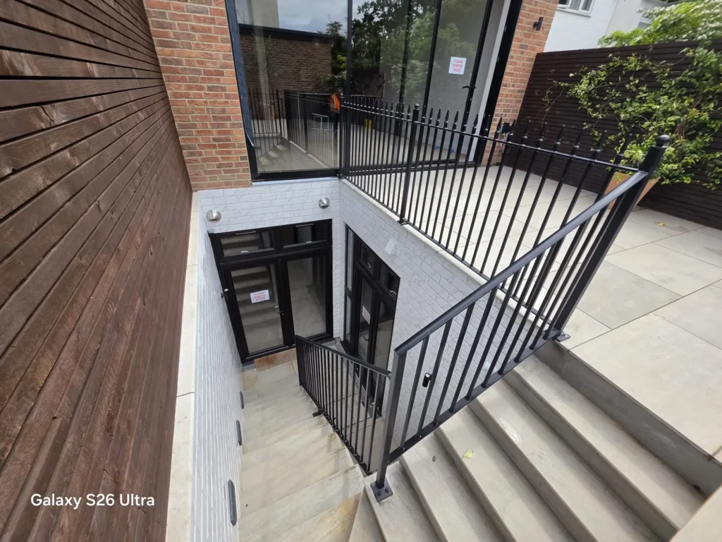 Bespoke black steel railings and handrails installed around external stairs and basement access by Franks Steel.